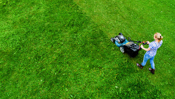 A woman mowing a green lawn